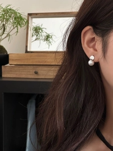 Primo piano dell'orecchino a perno in argento S925 con perla indossato da una modella