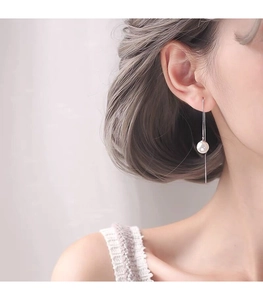 Detailed close-up of a long S925 silver chain earring with a white pearl on a model