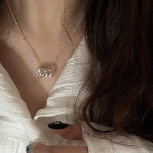 Detailed close-up of a silver triple-ring necklace worn with a white blouse