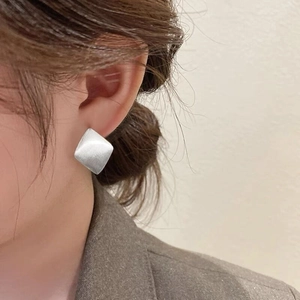 Detail of minimalist S925 sterling silver brushed geometric square hoop earrings on a model