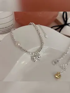 Detail of S925 sterling silver pearl bracelet with bow pendant on a ceramic plate