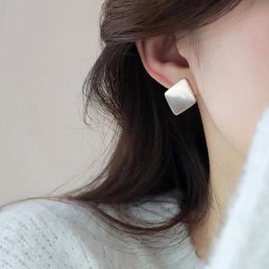 Close-up of a minimalist silver square earring with a brushed matte texture on ear