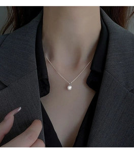 Dettaglio di una collana con ciondolo di perla bianca da 8mm indossata su un modello formale