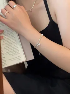 Detail of S925 silver beaded bracelet with bow pendant and pearl worn on wrist