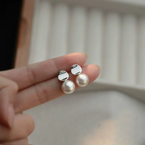Dettaglio degli eleganti orecchini di perle in argento S925 tenuti in mano per la misura