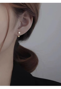 Macro view of S925 silver star earring with zircon inlay and hanging gold bead