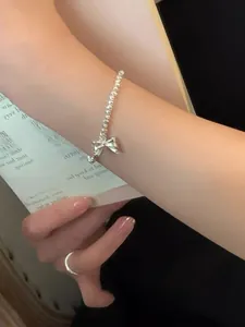 Detailed view of an S925 silver bow bracelet with matching ring on a person's wrist