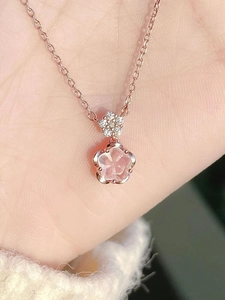 Detail view of rose gold cherry blossom necklace with pink stone petals on palm