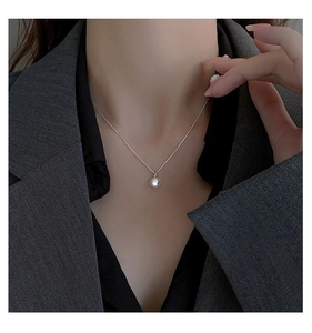 Dettaglio di elegante collana in argento S925 con perla bianca tonda su una modella