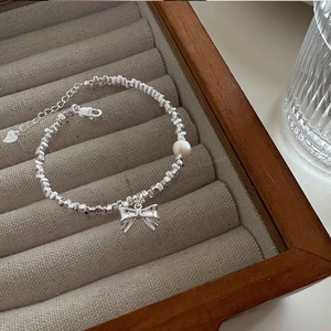 Detailed macro view of S925 silver bracelet featuring bow pendant and elegant white pearl