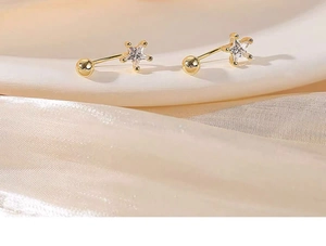 Macro view of gold star stud earring with a central clear zircon and screw back