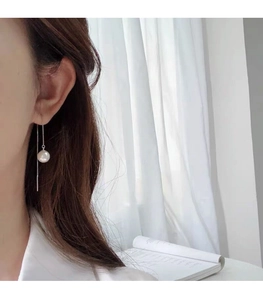 Elegant long S925 sterling silver chain earrings with glossy pearls worn in a soft setting