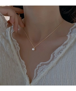 Collana minimalista in argento S925 con perla indossata su un top in pizzo bianco