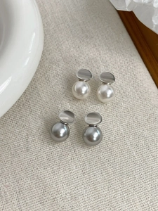 Dettaglio di eleganti orecchini in argento S925 con perle bianche e grigie su lino