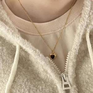 Detail of S925 silver heart necklace with black onyx pendant on gold beaded chain