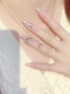 Detail of a rose gold sakura flower necklace with pink gemstone on a model