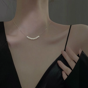 Détail d'un collier en argent S925 avec neuf perles blanches sur une fine chaîne argentée
