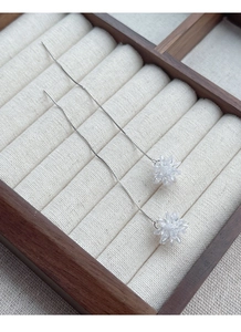 Close-up of S925 sterling silver tassel drop earrings with crystal flower in a wooden box