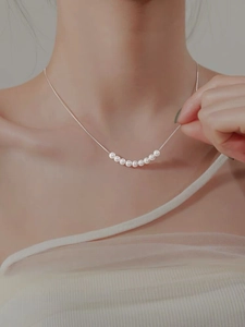 Gros plan de huit perles blanches sur un collier minimaliste en argent S925 sur peau