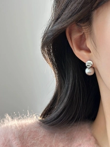 Dettaglio di orecchini a perno in argento S925 con perla grigia per uno stile elegante