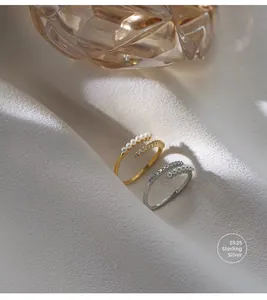 Detail of S925 sterling silver rings with layered pearls and zircon on white fabric