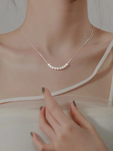 Gros plan du collier en argent S925 avec sept perles blanches sur le cou d'un mannequin