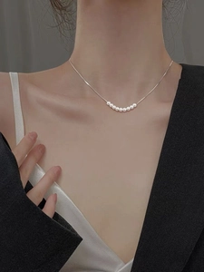 Collier en argent S925 orné de petites perles blanches porté par un modèle en costume