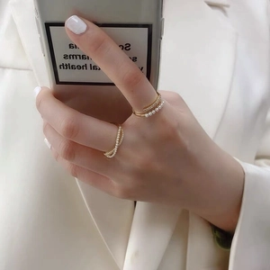 Detail of elegant gold-plated silver rings set with white pearls and zircons on fingers