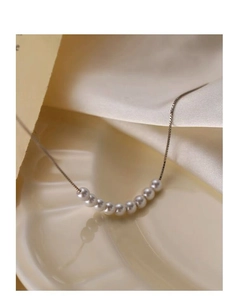 Détail d'un collier en argent S925 avec dix petites perles blanches sur tissu satiné