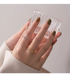 Detailed view of elegant silver and gold rings with white pearls and zircons on hand