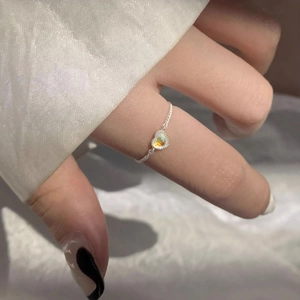 Macro shot of silver heart moonstone ring with rainbow sheen on silk background