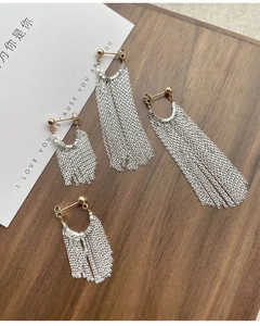 Vue détaillée de longues boucles d'oreilles à pompons argentés avec clous dorés