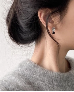 Detail of S925 silver stud earring with black onyx bead on female model for chic style