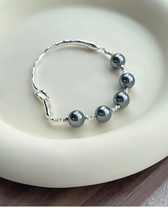 Detailed close-up of S925 sterling silver bangle with grey pearls on ceramic tray