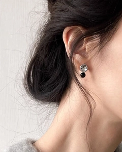 Detailed view of S925 silver stud earring with black bead on model's ear