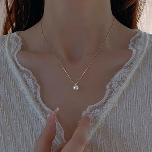 Elegante collana in argento S925 con pendente di perla bianca sul collo di una donna