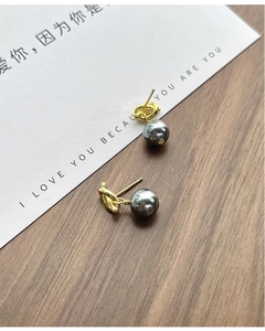 Detail of S925 silver knot pearl earrings on elegant wooden background with card