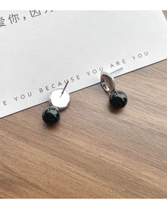 Detail of S925 silver black onyx stud earring on a white quote card and dark wood