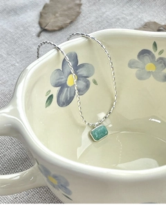 Detailed shot of S925 silver necklace with green amazonite pendant on a ceramic bowl