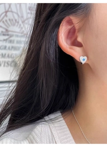 Détail de la boucle d'oreille cœur en argent S925 avec pierre bleue sur modèle