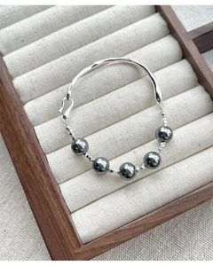 Detail of S925 silver bracelet with dark grey pearls and hammered texture on wood display