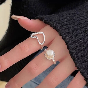 Dettaglio di anelli in argento S925 con texture lavica irregolare e perla d'acqua dolce bianca