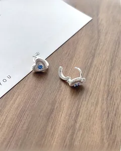 Détails de boucles d'oreilles cœur en argent avec pierre bleue sur bois texturé