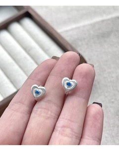 Vue macro de boucles d'oreilles cœur en argent S925 avec zircon bleu et texture nervurée