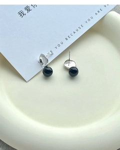 Close-up of S925 sterling silver black agate studs on a minimalist ceramic tray