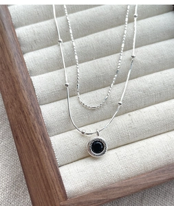 Detail of double-layer silver necklace with black onyx pendant on a jewelry tray
