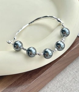 Detail of S925 silver bracelet featuring five lustrous dark grey pearls on a ceramic tray