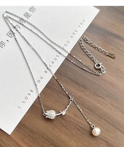 Macro detail of tulip pendant with shimmering zircon pavé and white pearl on S925 silver chain