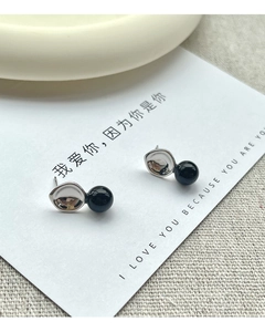 Macro detail of S925 silver stud earrings with black onyx bead on a linen background