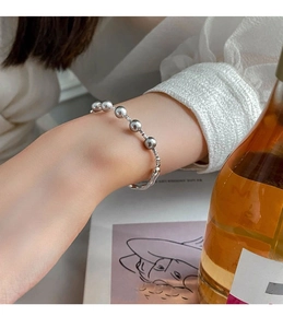 Detail of silver pearl bracelet on wrist with elegant fluid metal links and beads